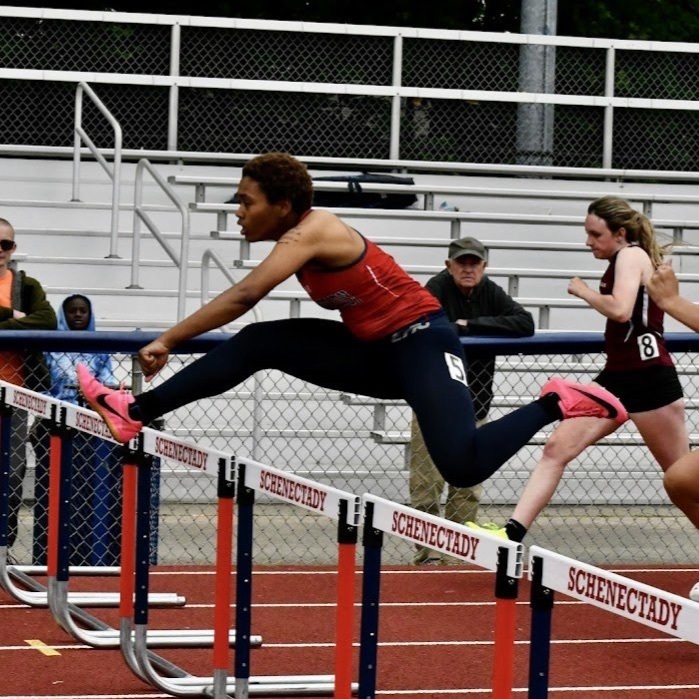 athlete jumps over hurdle